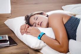 Moça deitada na cama com relógio medindo o sono